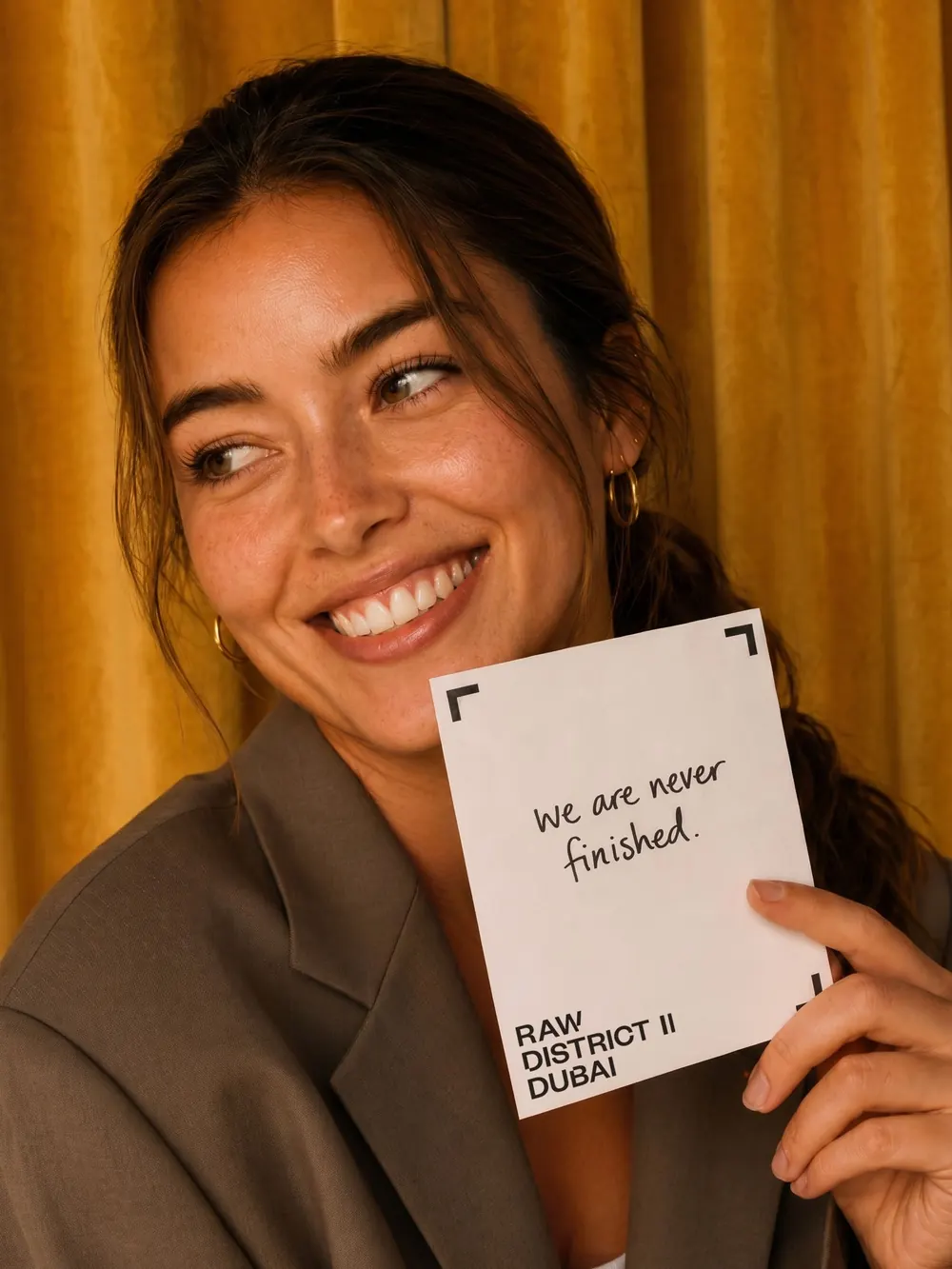 A smiling woman holding a card that reads: we are never finished